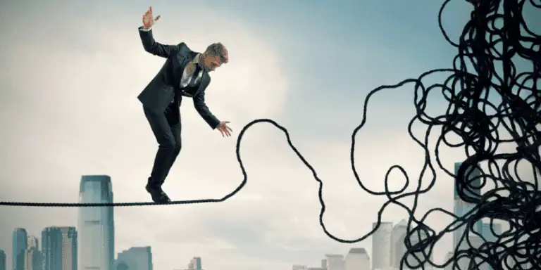 A man in a business suit carefully balances on a tightrope high above a city skyline, approaching a tangled mass of ropes, symbolizing navigating complex challenges or obstacles.