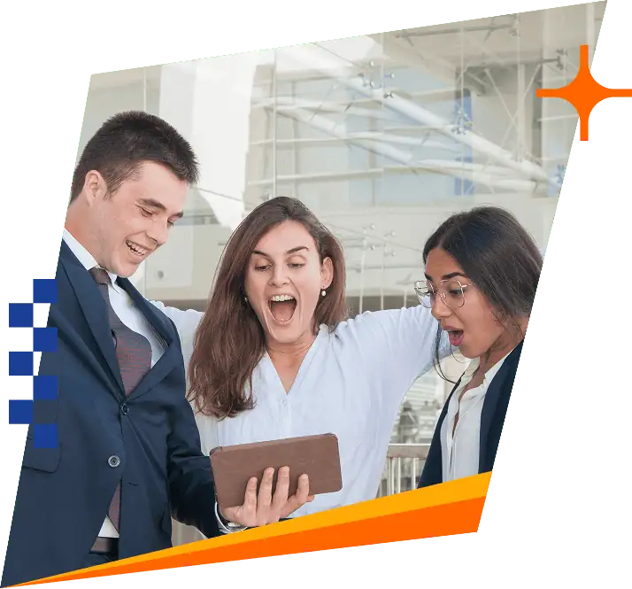 Three professionally dressed people stand together indoors, looking excitedly at a tablet one of them is holding. The background features modern architecture with glass and white structures.